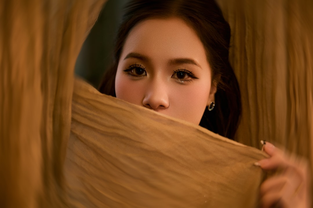 A woman peeking from behind a golden cloth.