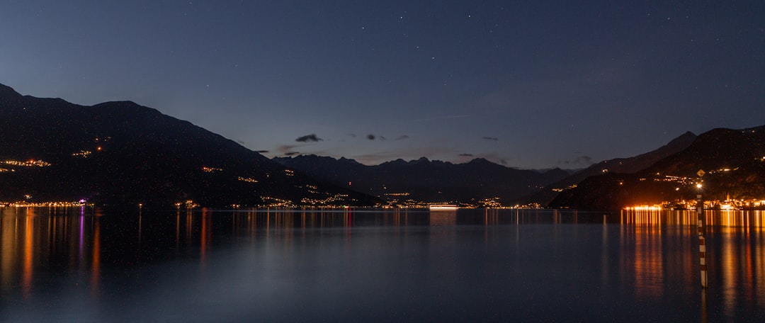 A body of water at night with mountains in the background